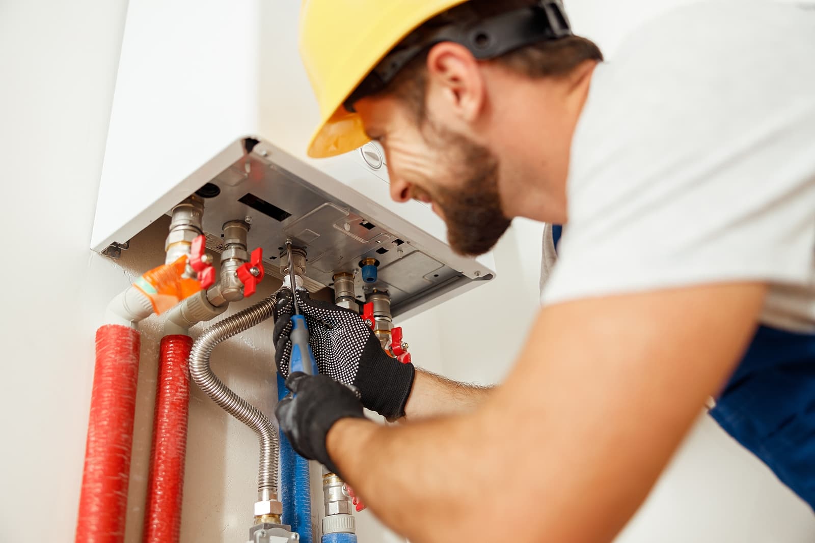 boiler installation surbiton - plumber using screwdriver while fixing boiler